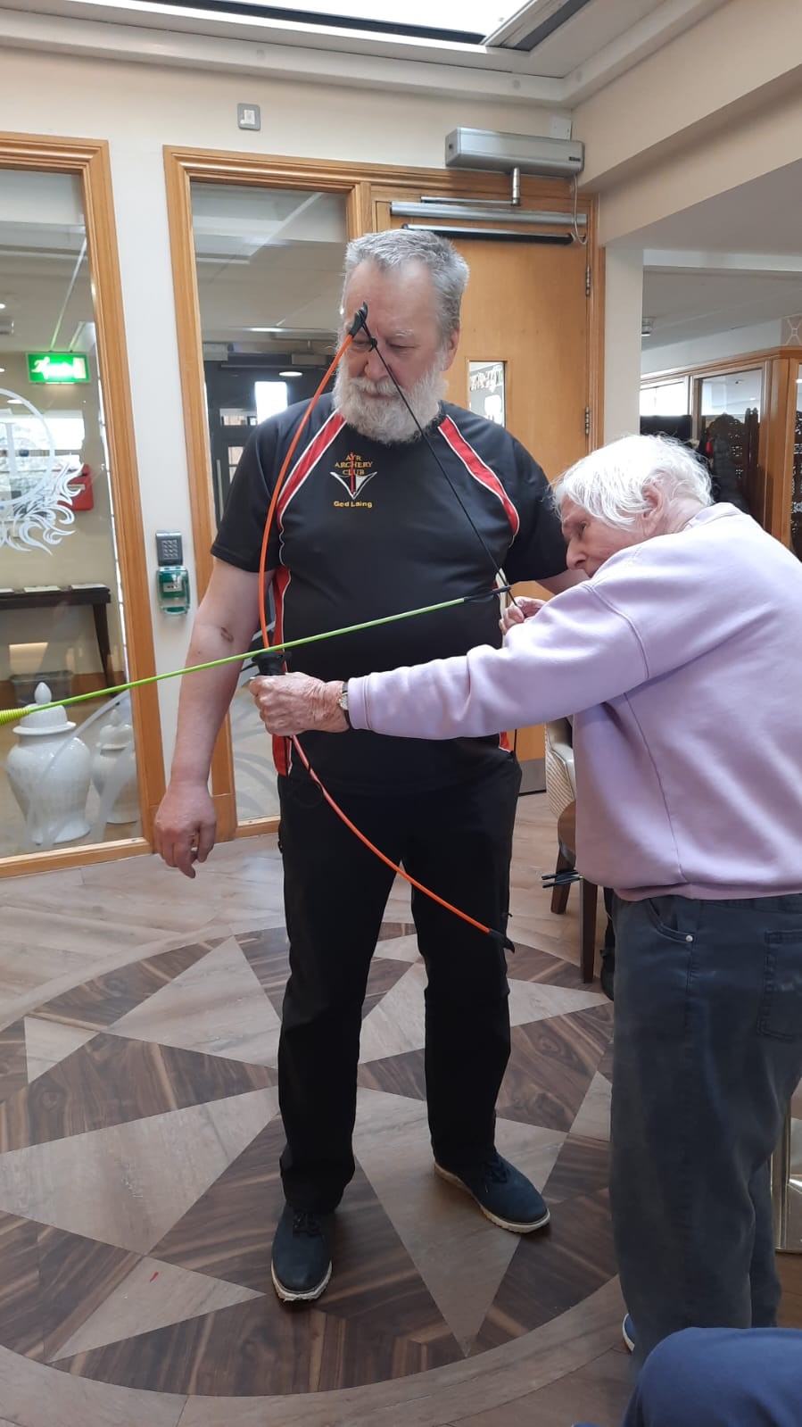 Resident Partaking in Archery With The Help of Jed