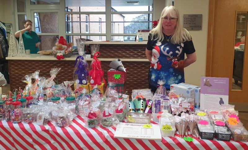Woman standing behind indoor Christmas Market stall